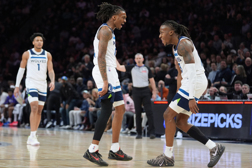 Minnesota Timberwolves guards Bones Hyland (8), middle, and Ayo Dosunmu (13), right, celebrate during a timeout in the first half of an NBA basketball game against the Utah Jazz, Wednesday, March 18, 2026, in Minneapolis. (AP Photo/Abbie Parr)