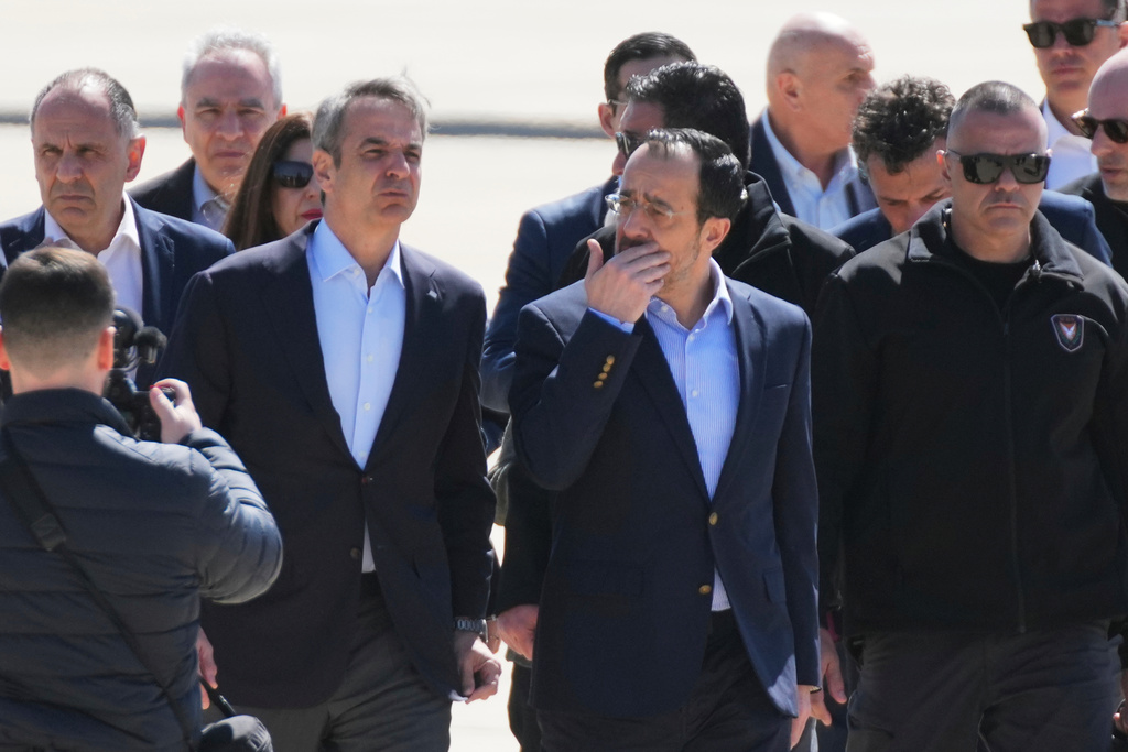 Greece's Prime Minister Kyriakos Mitsotakis, left, is welcomed by Cyprus President Nikos Christodoulides, second right, ahead of their meeting with French President Emmanuel Macron at Andreas Papandreou Air Base in Paphos, Cyprus, on Monday, March 9, 2026. (AP Photo/Petros Karadjias)