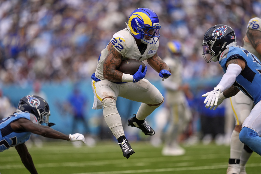 Los Angeles Rams running back Blake Corum, center, runs the ball as Tennessee Titans cornerback Jarvis Brownlee Jr., left, and safety Amani Hooker defend during the second half of an NFL football game Sunday, Sept. 14, 2025, in Nashville, Tenn. (AP Photo/George Walker IV)