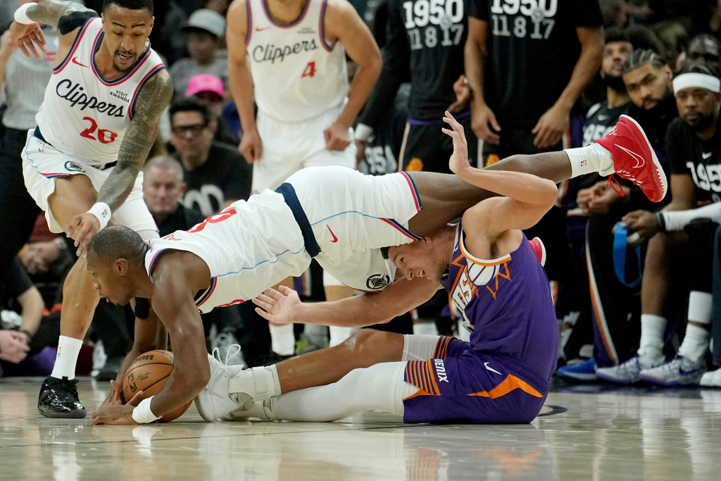 Los Angeles Clippers guard Kris Dunn, left, battles with Phoenix Suns guard Grayson Allen, right, for a loose ball as Clippers forward John Collins (20) looks for the ball during the first half of an NBA basketball game Sunday, Feb. 1, 2026, in Phoenix. (AP Photo/Ross D. Franklin)