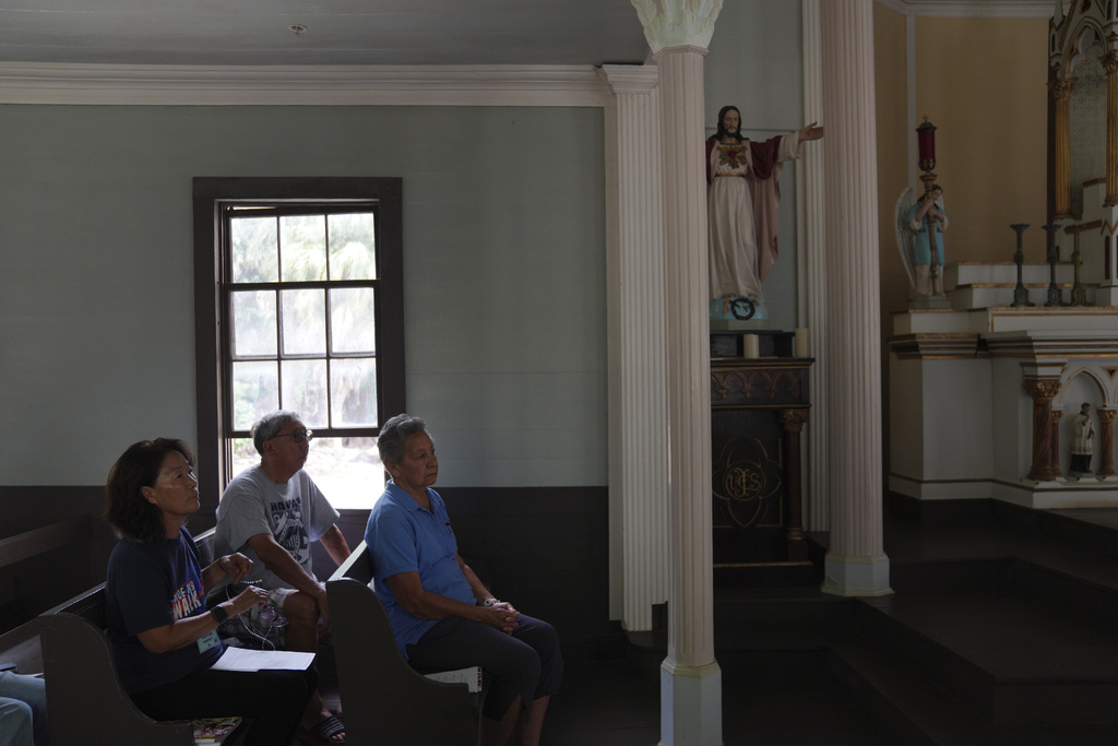FILE - Kyong Son Toyofuku, left, her husband, Lance Toyofuku, center, and sister Alicia Damien Lau, celebrate Mass at St. Philomena Church during a pilgrimage tour of Kalaupapa, Hawaii, July 18, 2023. (AP Photo/Jessie Wardarski, File)