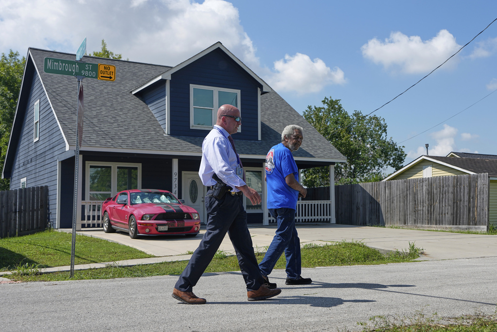 Neighbor George Skinner, right, talks a police investigator outside a home Tuesday, Sept. 2, 2025, in Houston, near the location where 11-year-old Julian Guzman was shot and killed during a doorbell prank, according to police. (AP Photo/David J. Phillip)