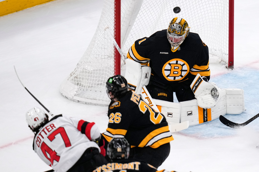 Boston Bruins goaltender Jeremy Swayman (1) makes a save on a shot by New Jersey Devils left wing Paul Cotter (47) during the first period of a hockey game, Tuesday, April 14, 2026, in Boston. (AP Photo/Charles Krupa)