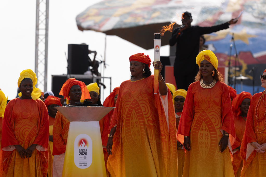 Senegalese basketball legend Mame Maty Mbengue lights a torch from the cauldron during a ceremony ahead of the Dakar 2026 Youth Olympic Games, in Dakar, Senegal, Saturday, Sept. 12, 2026. (AP Photo/Sylvain Cherkaoui)