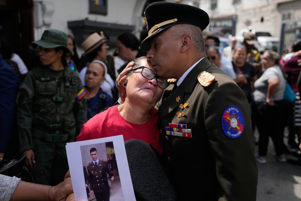 A military officer comforts Ramona Palma, the mother of Venezuelan soldier Cesar Garcia, who was killed in a U.S. raid that captured Venezuelan President Nicolas Maduro, after Garcia's wake in Caracas, Venezuela, Wednesday, Jan. 7, 2026. (AP Photo/Matias Delacroix)