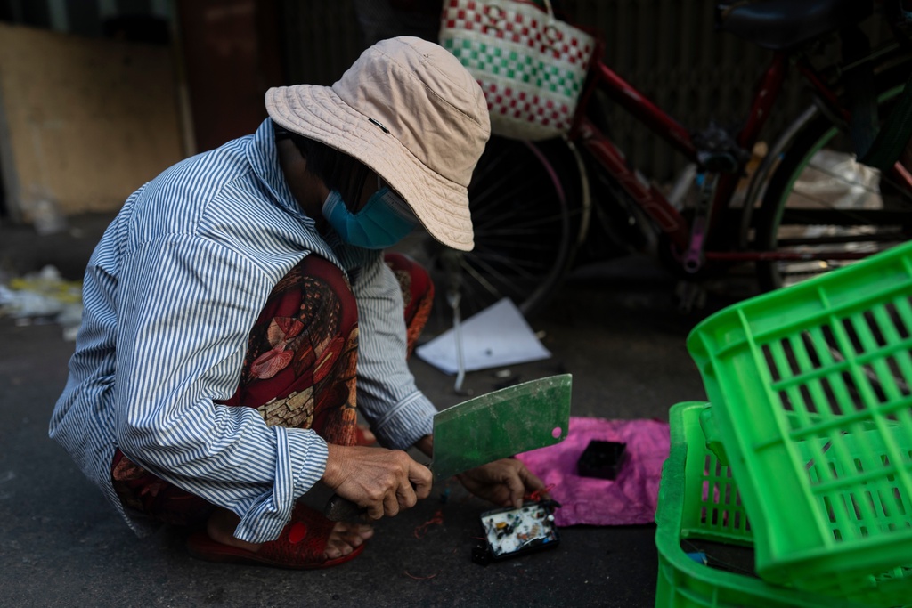 FILE - An e -waste collector uses a cleaver to remove copper wire from a device in Nhat Tao market, the largest informal recycling market in Ho Chi Minh City, Vietnam, Jan. 31, 2024. (AP Photo/Jae C. Hong, File)