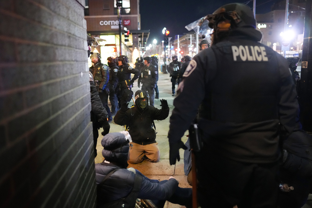 A protester raises their arms on the ground as law enforcement make arrests after declaring an unlawful assembly during a noise demonstration outside the Graduate by Hilton Minneapolis hotel on Wednesday, Jan. 28, 2026, in Minneapolis. (AP Photo/Adam Gray)