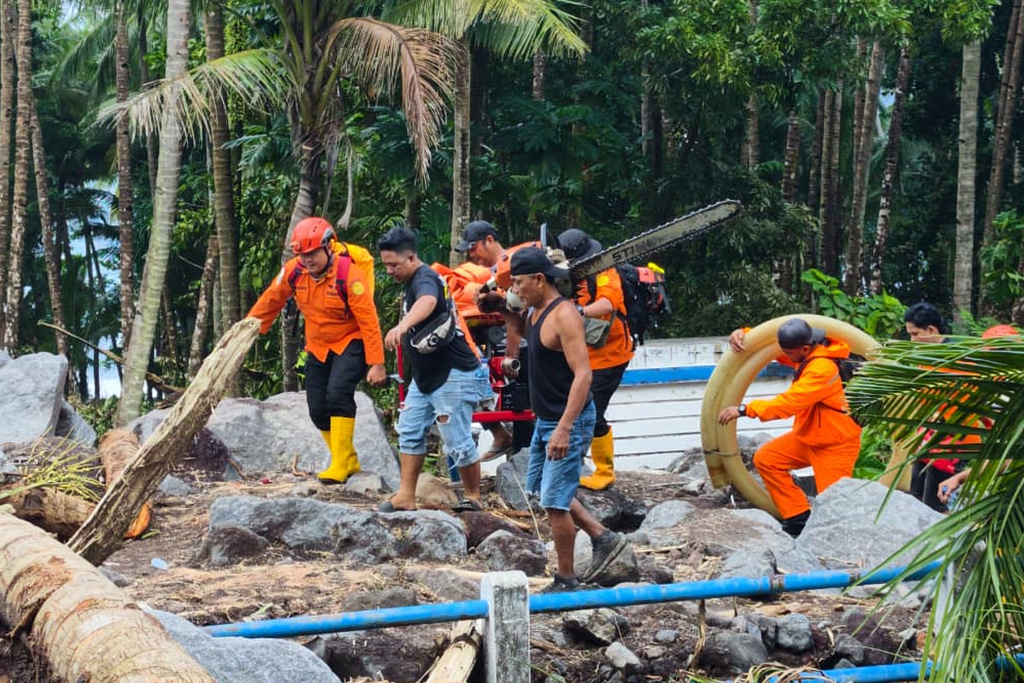 In this photo released by the Indonesian National Search and Rescue Agency (BASARNAS) on Tuesday, Jan. 6, 2026, rescuers and villagers search for victims after flash floods hit Sitaro district of North Sulawesi province, Indonesia. (BASARNAS via AP)