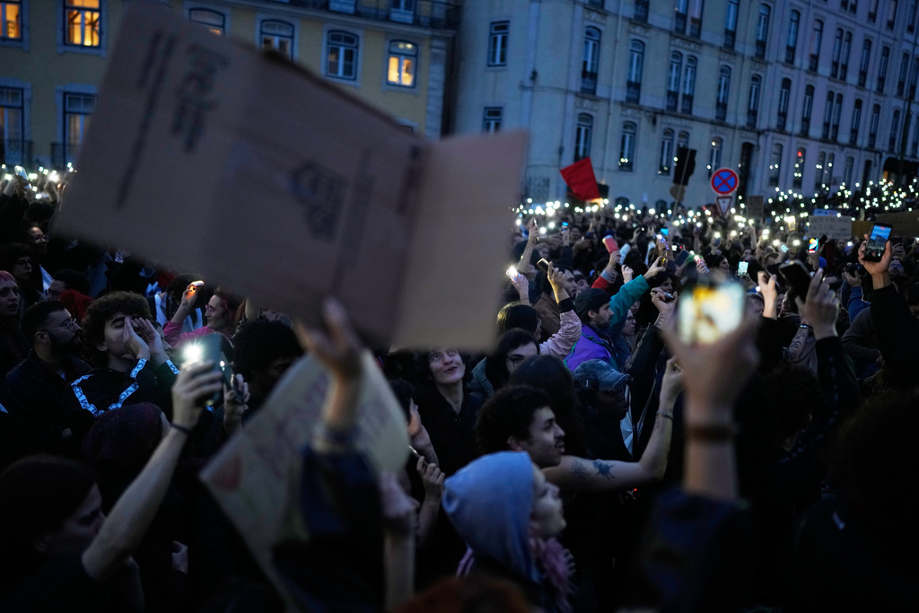 People hold up their cellphones outside the parliament in Lisbon during a general strike to protest against a new labour package announced by the centre-right government Thursday, Dec. 11, 2025. (AP Photo/Armando Franca)