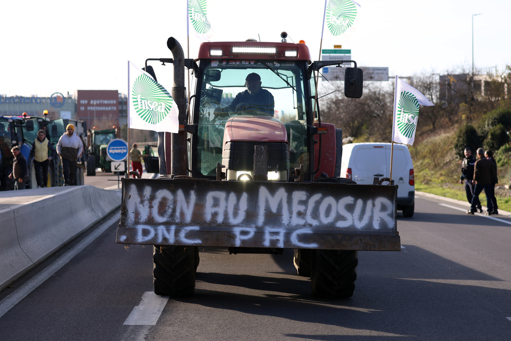 A French farmer drives his tractor to block a main road during a protest against the Mercosur trade deal with South American nations, Thursday, Dec. 18, 2025 in Portet-sur-Garonne, southwestern France. (AP Photo/Fred Scheiber)