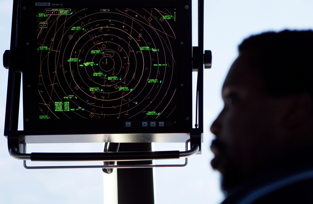 FILE - In this Sept. 18, 2008, file photo an air traffic controller stands beneath a radar screen in the control tower at Washington's Reagan National Airport. (AP Photo/Charles Dharapak, File)
