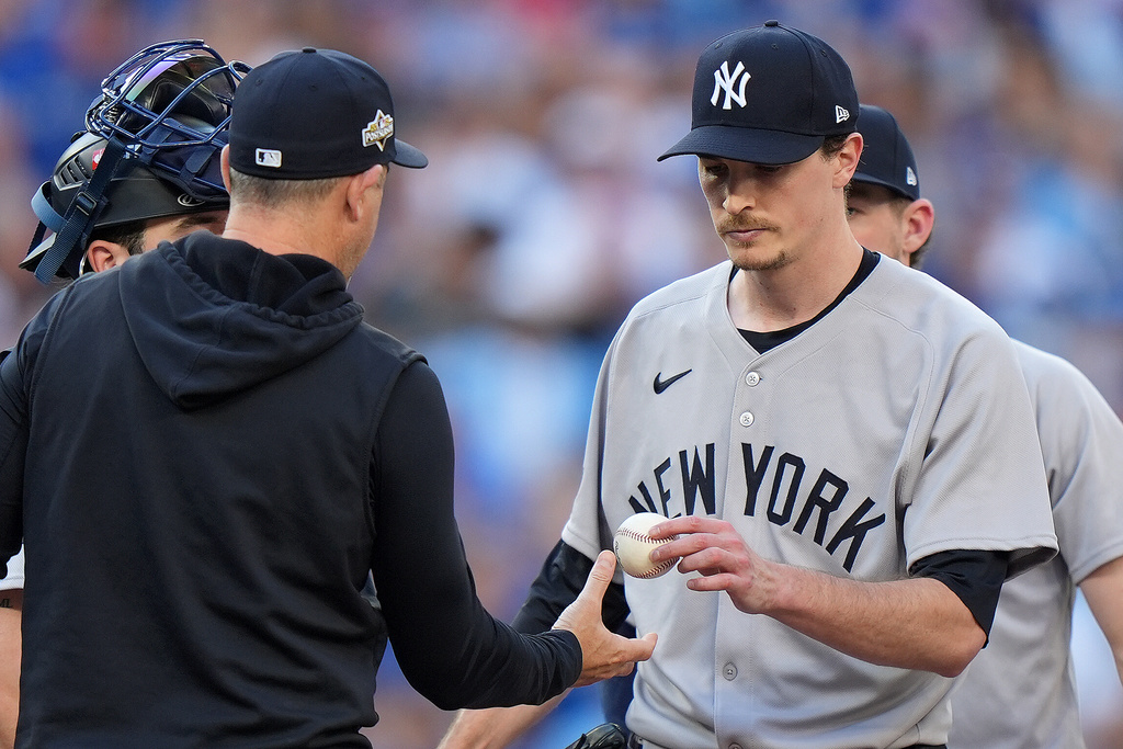 New York Yankees pitcher Max Fried, right, hands the ball to Yankees manager Aaron Boone, left, as he is pulled from the mound during the fourth inning of Game 2 of baseball's American League Division Series against the Toronto Blue Jays in Toronto, Sunday, Oct. 5, 2025. (Frank Gunn/The Canadian Press via AP)