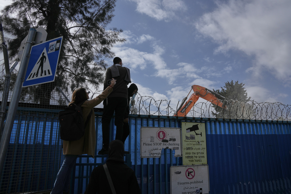 People watch the demolition of a UNRWA compound, the U.N. agency that assists Palestinian refugees, in east Jerusalem Tuesday, Jan. 20, 2026. (AP Photo/Mahmoud Illean)