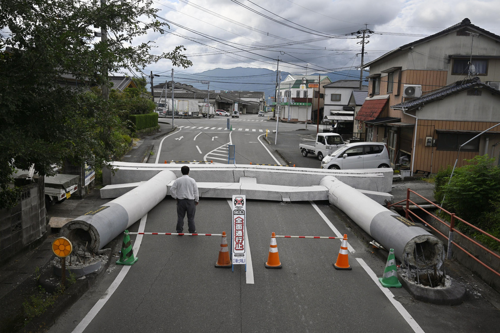 People stand by the fallen torii gate near a shrine, a day after an earthquake in Yatsushiro, Kumamoto prefecture, Wednesday, July 29, 2026.(Yu Nakajima/Kyodo News via AP)
