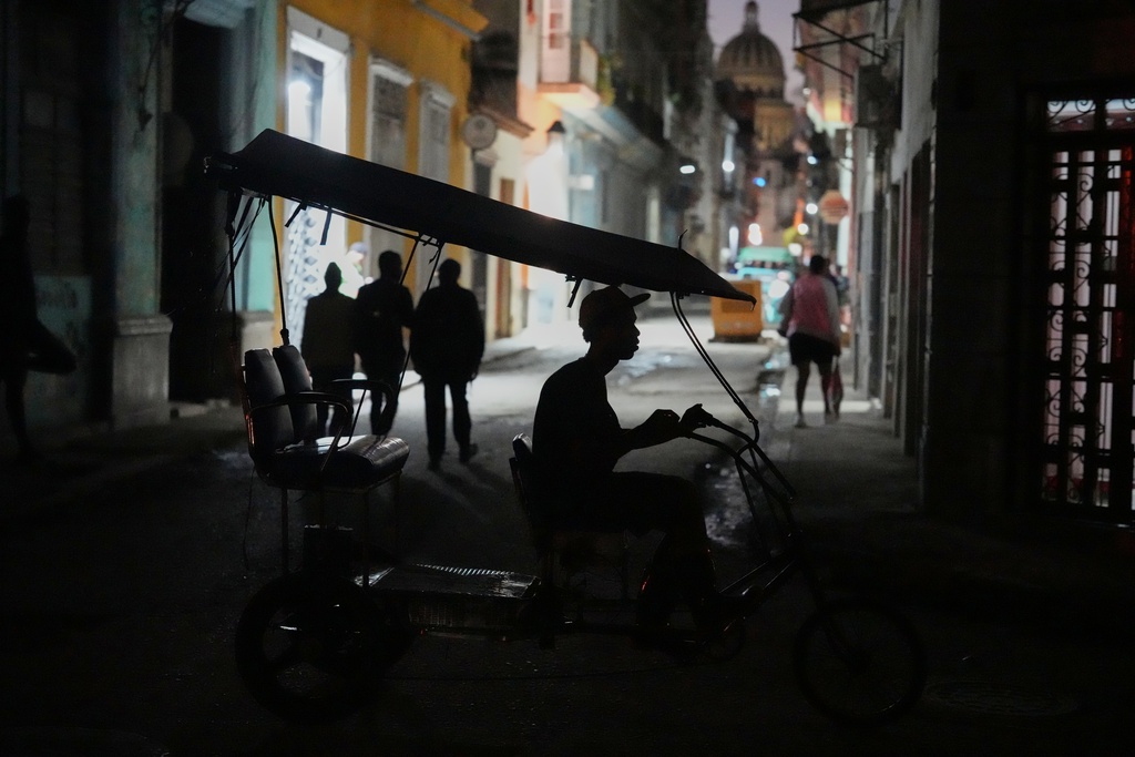 A bicycle taxi traverses a road at night in Havana, Tuesday, Jan. 6, 2026. (AP Photo/Ramon Espinosa)