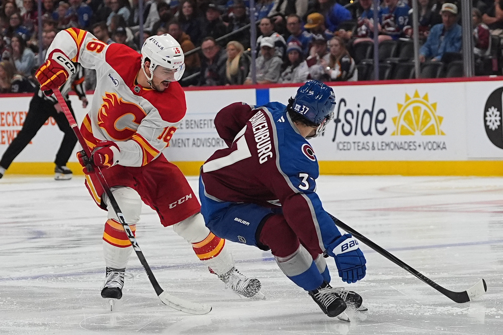 Calgary Flames center Morgan Frost, left, loses control of the puck to Colorado Avalanche defenseman Nick Blankenburg in the second period of an NHL hockey game Thursday, April 9, 2026, in Denver. (AP Photo/David Zalubowski)