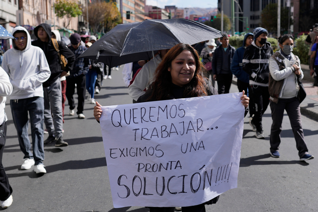 A vendor carries a sign reading in Spanish "We want to work, we demand a prompt solution," during a march against protesters who are blocking access to La Paz, Bolivia, Monday, June 8, 2026. (AP Photo/Juan Karita)
