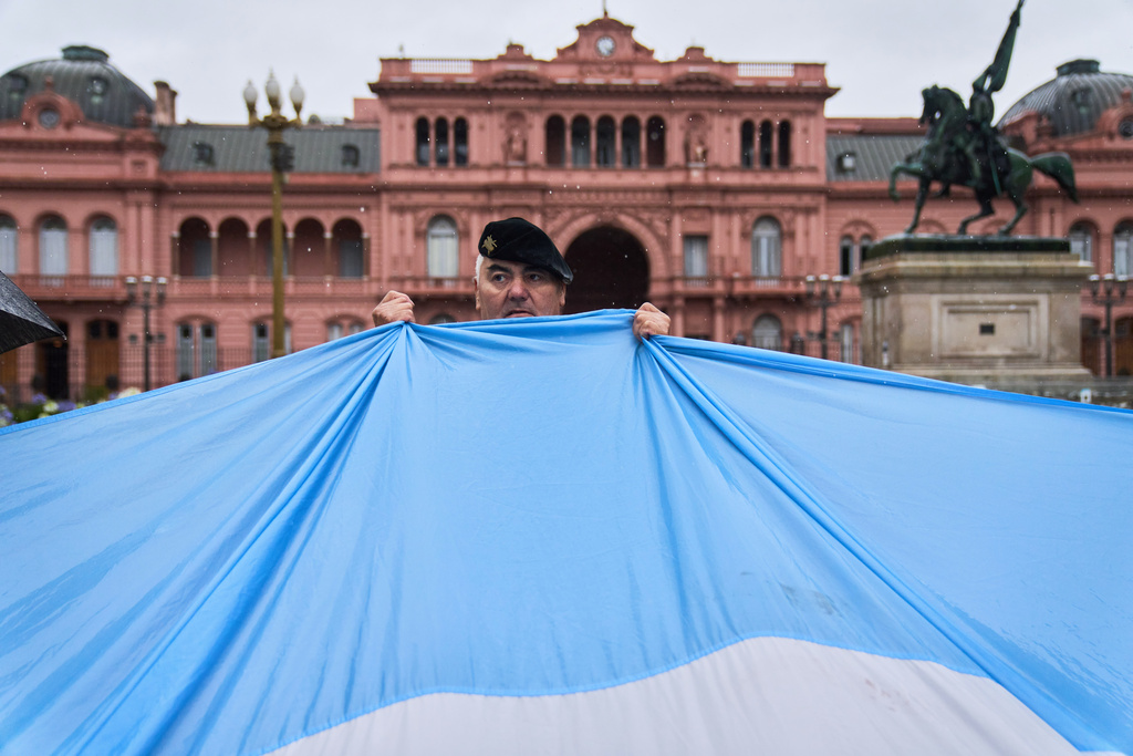 A retired military officer holds an Argentine flag in front of the presidential palace during a protest demanding the release of former servicemen accused of human rights violations during the last dictatorship, in Buenos Aires, Argentina, Saturday, Nov. 29, 2025. (AP Photo/Rodrigo Abd)