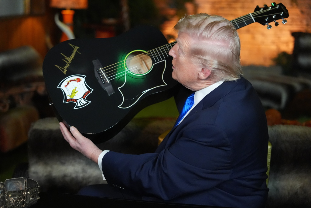 President Donald Trump holds up replica of a Elvis Presley guitar he had just signed, in the Jungle Room at Graceland, Elvis Presley's historic estate, Monday, March 23, 2026, in Memphis, Tenn. (AP Photo/Mark Schiefelbein)
