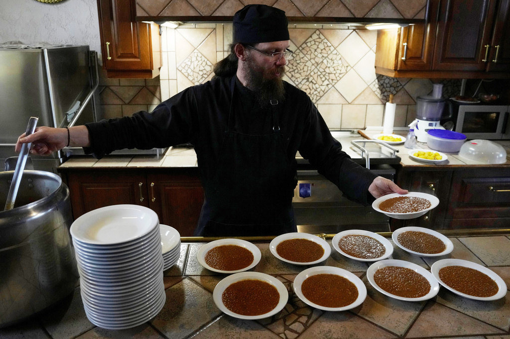 Father Isaac serves lentils for the midday meal at the Monastery of St. Augustine and Seraphim of Sarov in the village of Trikorfo, about 236 kilometers (147 miles) northwest of Athens, Friday, March 20, 2026. (AP Photo/Thanassis Stavrakis)