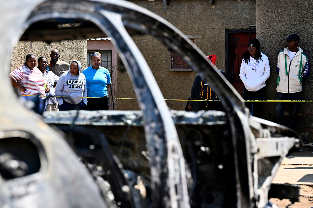 Community members stand at scene of a mass shooting on Saturday night when suspects opened fire at a bar in Wedela township, southwest of Johannesburg, South Africa, Sunday, Sept. 27, 2026. (AP Photo)
