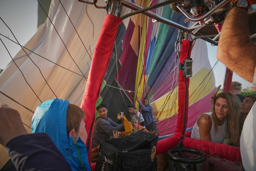 Tourists chat as ground crew members retrieve their hot air balloon after landing on the west bank of the Nile River in Luxor, Egypt, Oct. 4, 2025. (AP Photo/Amr Nabil)