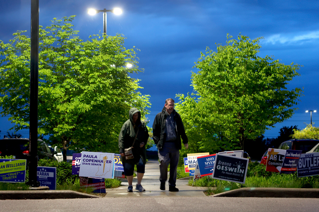 People walk through signs in a front of a vote center during a primary election on Tuesday, May 5, 2026, in West Lafayette, Ind. (AP Photo/Cara Penquite)