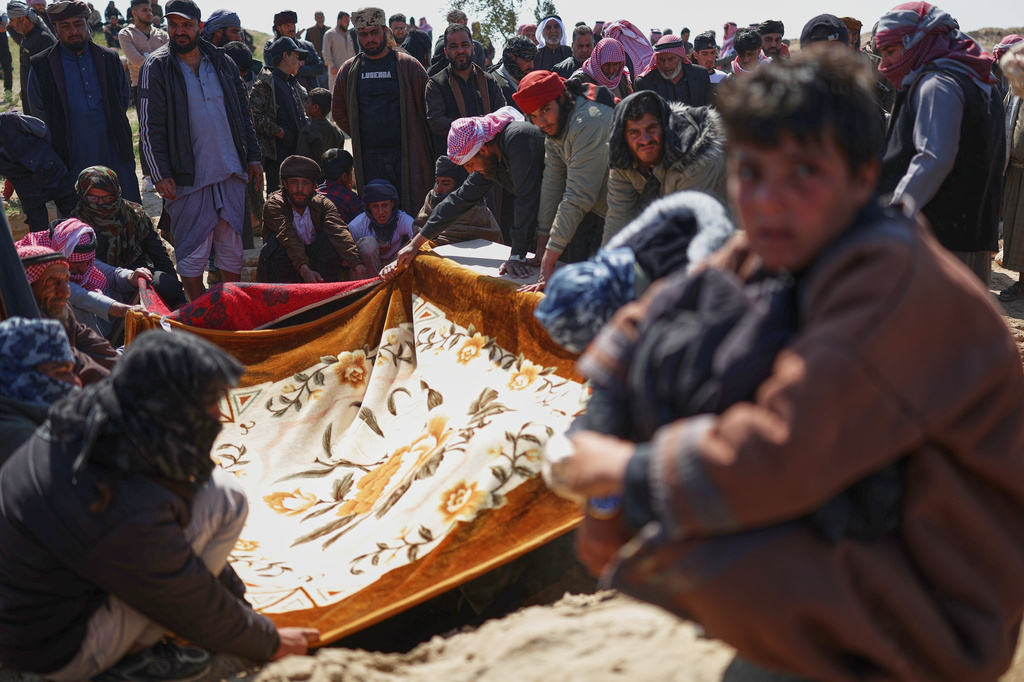 Mourners cover a grave with cloth during the burial of a woman from the Al-Jalib family, among six relatives killed Wednesday in Israeli strikes in Beirut, during their funeral in the village of al-Sour, Deir al-Zour province, northeastern Syria, Saturday, April 11, 2026. The cloth is held to preserve privacy and shield the body from view.(AP Photo/Ghaith Alsayed)