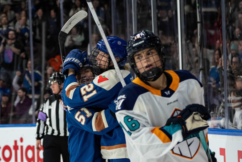 Vancouver Goldeneyes' Ashton Bell (21) celebrates her goal with Anna Segedi (51) as New York Sirens' Lauren Bernard (16) skates away during the first period of a PWHL hockey game in Vancouver on Saturday, Dec. 6, 2025. (Ethan Cairns/The Canadian Press via AP)