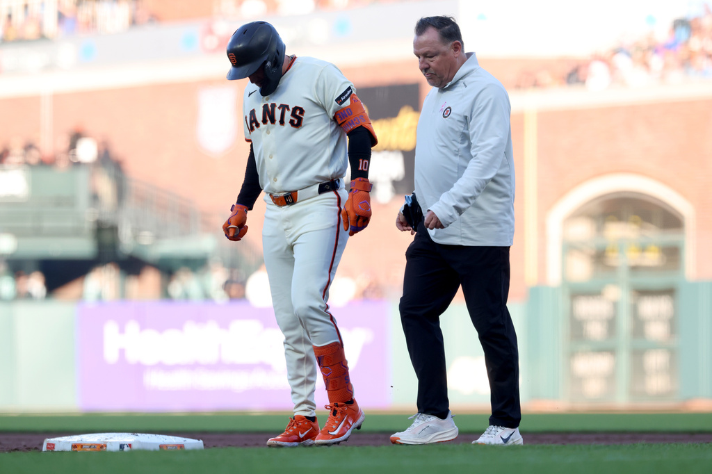 San Francisco Giants' Casey Schmitt, left, walks off the field with an injury accompanied by athletic trainer Dave Groeschner, right, during the second inning of a baseball game against the Milwaukee Brewers in San Francisco, Monday, July 27, 2026. (AP Photo/Jed Jacobsohn)