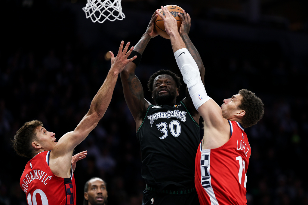 Minnesota Timberwolves forward Julius Randle, middle goes up for a shot as Los Angeles Clippers center Brook Lopez (11) and guard Bogdan Bogdanovic (10) defend during the first half of an NBA basketball game Saturday, Dec. 6, 2025, in Minneapolis. (AP Photo/Matt Krohn)