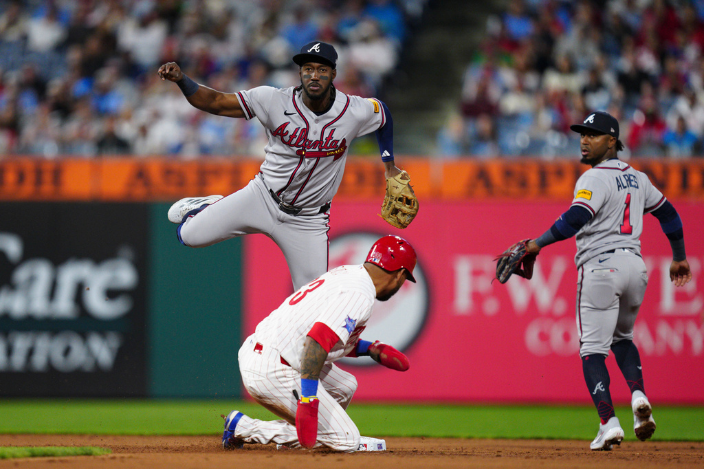 Atlanta Braves' Jorge Mateo, top center, throws to first base for a double play over Philadelphia Phillies' Edmundo Sosa during the fifth inning of a baseball game, Saturday, April 18, 2026, in Philadelphia. Phillies' Brandon Marsh was out at first. (AP Photo/Derik Hamilton)