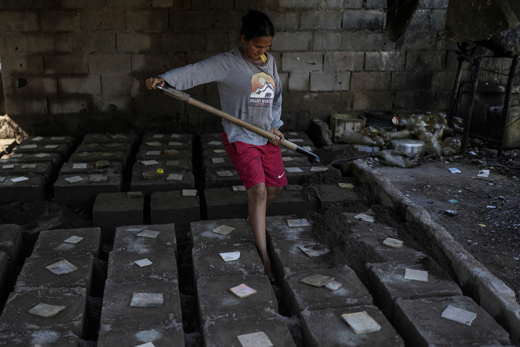 Yosbelin Perez, who returned to Venezuela from Mexico with her husband and five children after abandoning plans to reach the United States amid President Donald Trump's migration crackdown, covers molds with molten aluminum to make griddles, in Maracaibo, Venezuela, Monday, June 16, 2025. (AP Photo/Matias Delacroix)