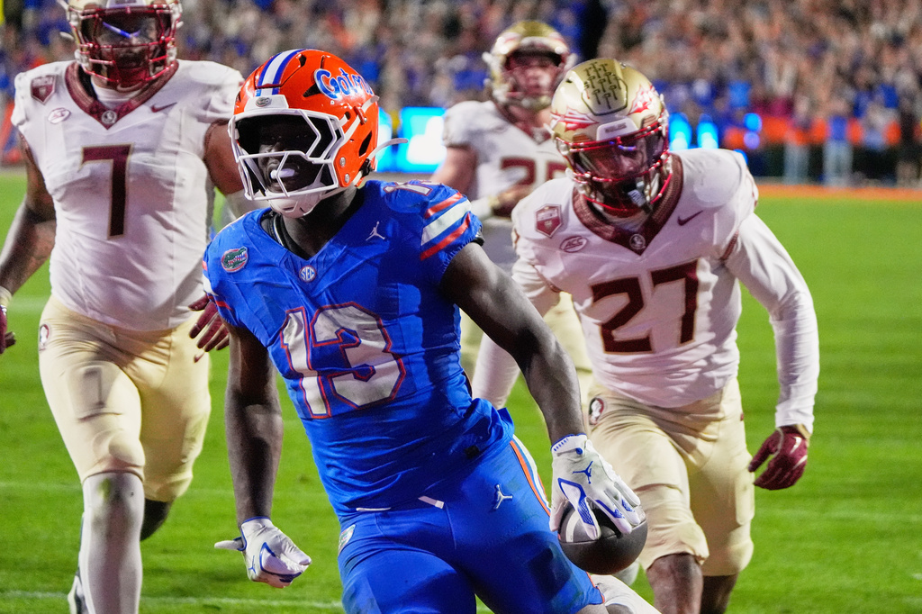 FILE - Florida running back Jadan Baugh (13) runs past Florida State defensive back Ashlynd Barker (27) for a touchdown during the second half of an NCAA college football game, Nov. 29, 2025, in Gainesville, Fla. (AP Photo/John Raoux, File)