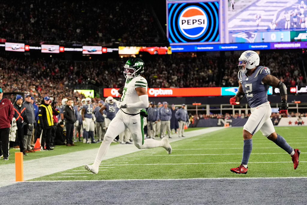 New York Jets quarterback Justin Fields scores a touchdown past New England Patriots' Harold Landry III during the first half of an NFL football game, Thursday, Nov. 13, 2025, in Foxborough, Mass. (AP Photo/Charles Krupa)
