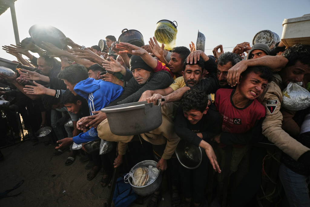 Displaced Palestinian struggle to receive donated food for iftar, the fast-breaking meal, on the first day of the Muslim holy month of Ramadan at a community kitchen in Khan Younis, Gaza Strip, Wednesday, Feb. 18, 2026. (AP Photo/Jehad Alshrafi)