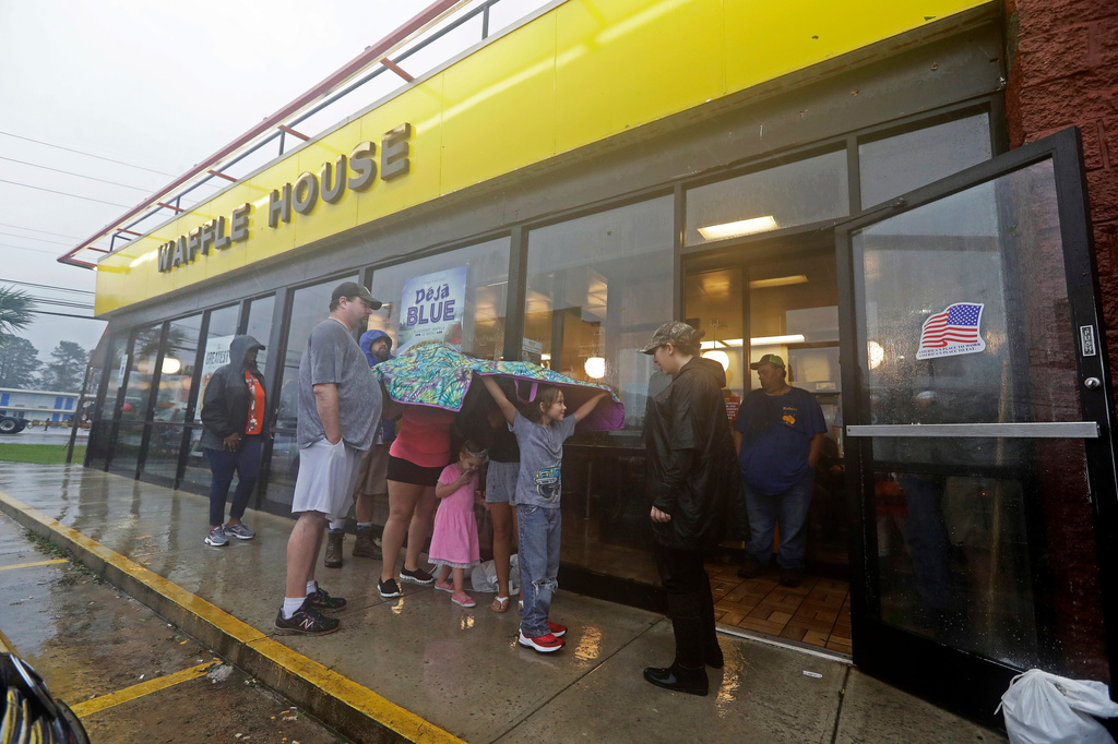 FILE - Luke Churchill, left, stands with his wife Mary and their children, Katie, Liam and Raighan, as they wait in the rain outside an open Waffle House restaurant in Wilmington, N.C., after Hurricane Florence traveled through the area on Sept. 16, 2018. (AP Photo/Chuck Burton, File)