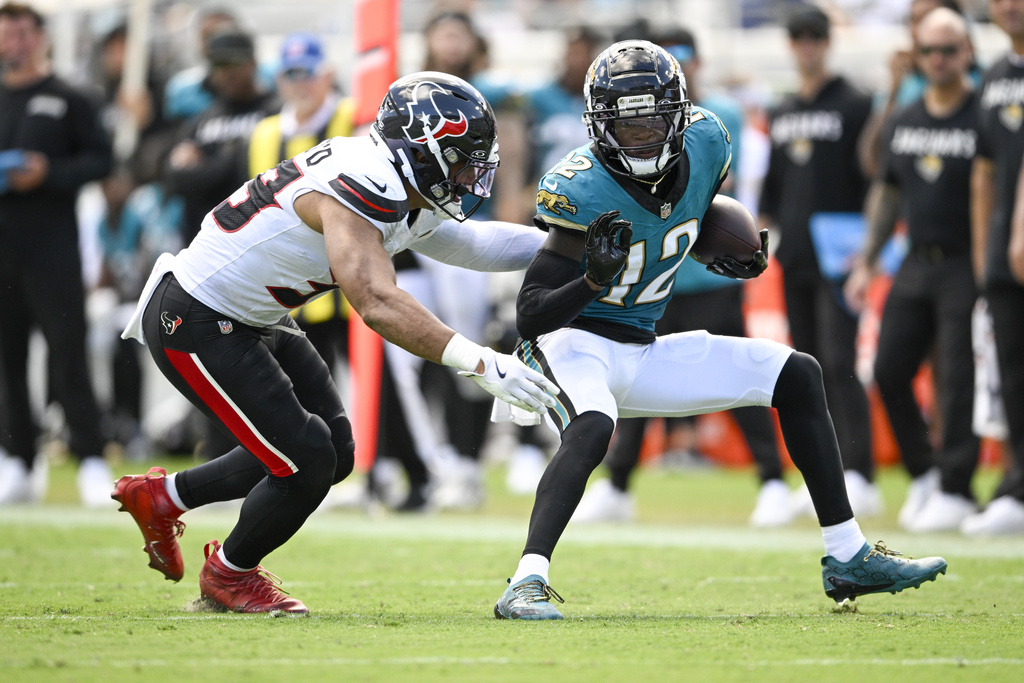 Jacksonville Jaguars wide receiver Travis Hunter, right, tries to avoid a tackle by Houston Texans linebacker Henry To'Oto'O after making a catch during the second half of an NFL football game Sunday, Sept. 21, 2025, in Jacksonville, Fla. (AP Photo/Phelan M. Ebenhack)