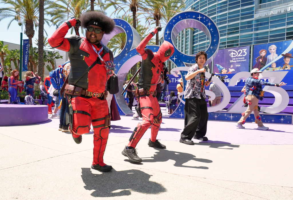 Mohamed Obsidye, left, of Columbus, Ohio, dressed as his own superhero character "Afro-Pool," leads a dance outside the entrance to D23: The Ultimate Disney Fan Event on Friday, Aug. 14, 2026, at the Anaheim Convention Center in Anaheim, Calif. (AP Photo/Chris Pizzello)