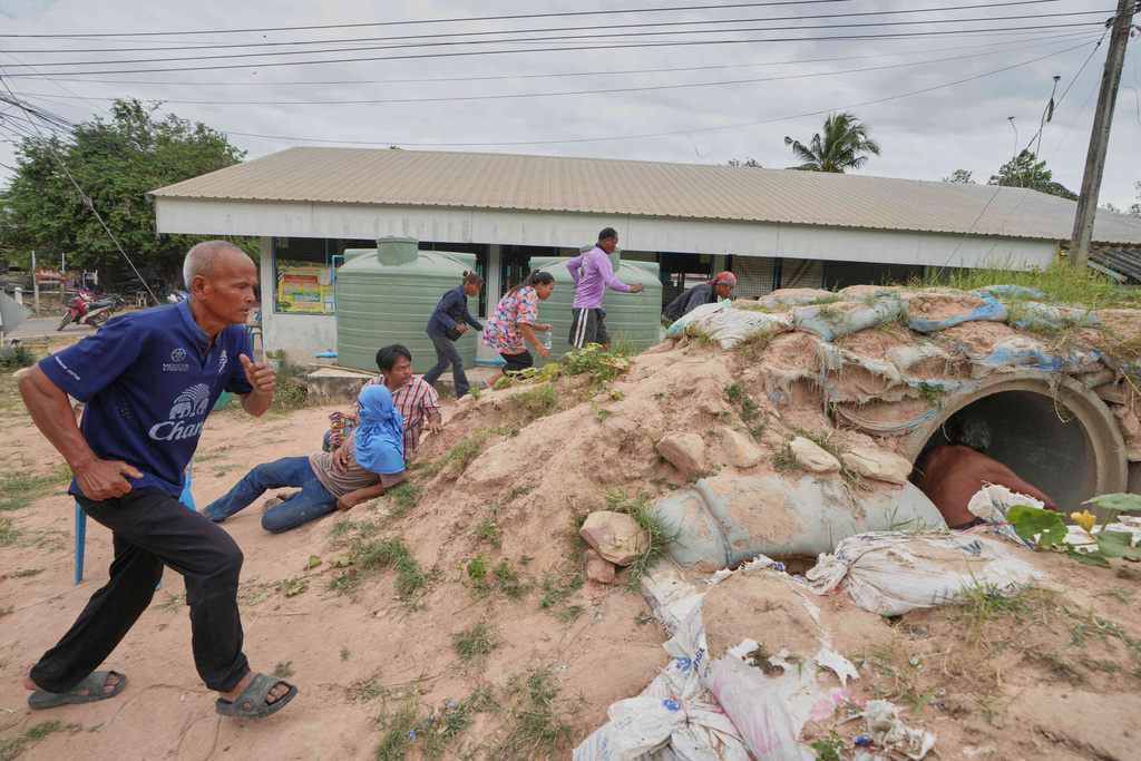Village security volunteers and resident run into shelter while the blasts sounded too close in Buriram province, Thailand, Friday, Dec. 12, 2025, following renewed border conflict between Thailand and Cambodia. (AP Photo/Sakchai Lalit)