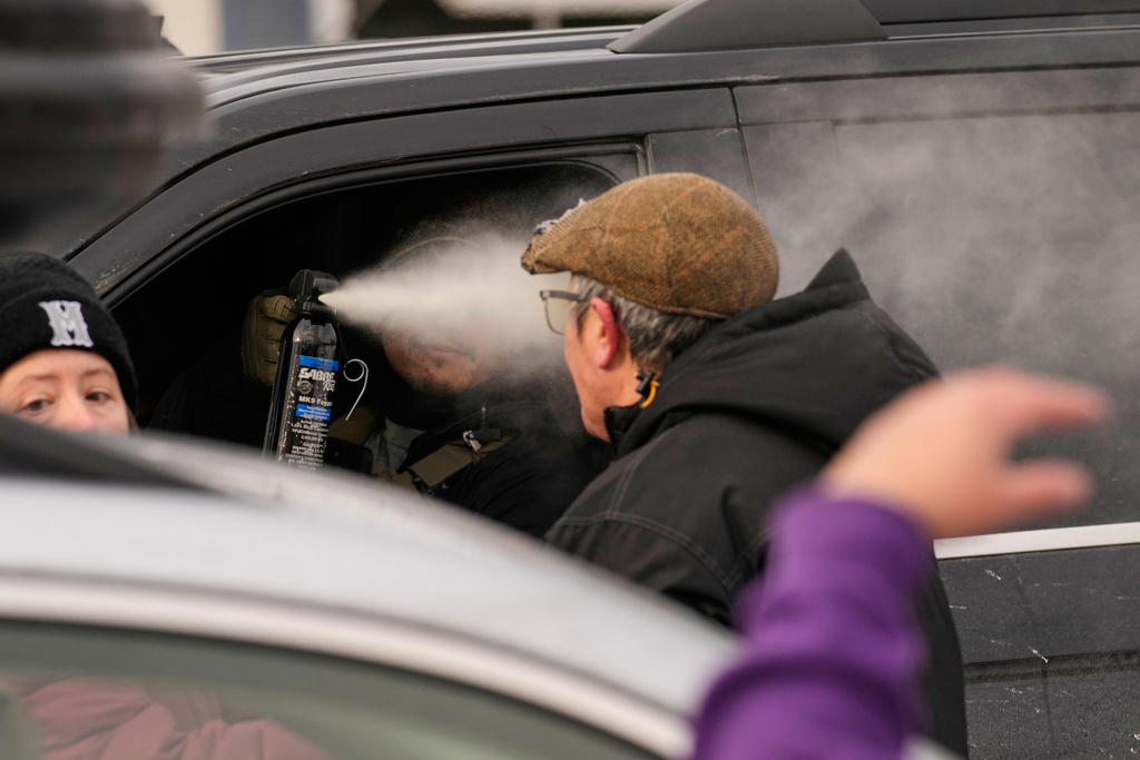 A federal immigration officer deploys pepper spray as officers make an arrest Sunday, Jan. 11, 2026, in Minneapolis. (AP Photo/John Locher)