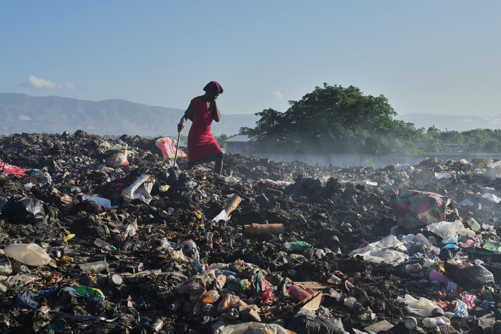 A woman searches garbage for items to use or sell in the Tabarre neighborhood of Port-au-Prince, Haiti, Monday, March 16, 2026. (AP Photo/Odelyn Joseph)