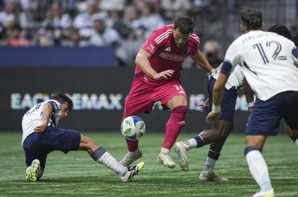 St. Louis City's Eduard Lowen, centre, tries to move the ball past Vancouver Whitecaps Andres Cubas, left, and Emmanuel Sabbi, back right, during the first half of an MLS soccer match, in Vancouver, on Saturday, August 23, 2025. (Darryl Dyck/The Canadian Press via AP)