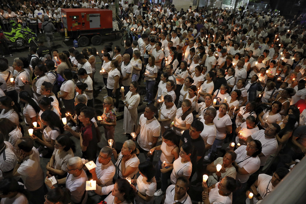 People hold candles outside the Air Force base in Cali, Colombia, during a vigil to honor the victims of a car bomb that exploded there three days earlier, Sunday, Aug. 24, 2025. (AP Photo/Santiago Saldarriaga)