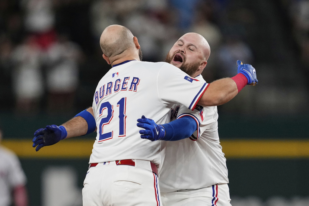 Texas Rangers' Jake Burger (21) and Rowdy Tellez, right, celebrate Burger's run-scoring single in the 10th inning of a baseball game against the Arizona Diamondbacks Monday, Aug. 11, 2025, in Arlington, Texas. (AP Photo/Tony Gutierrez)