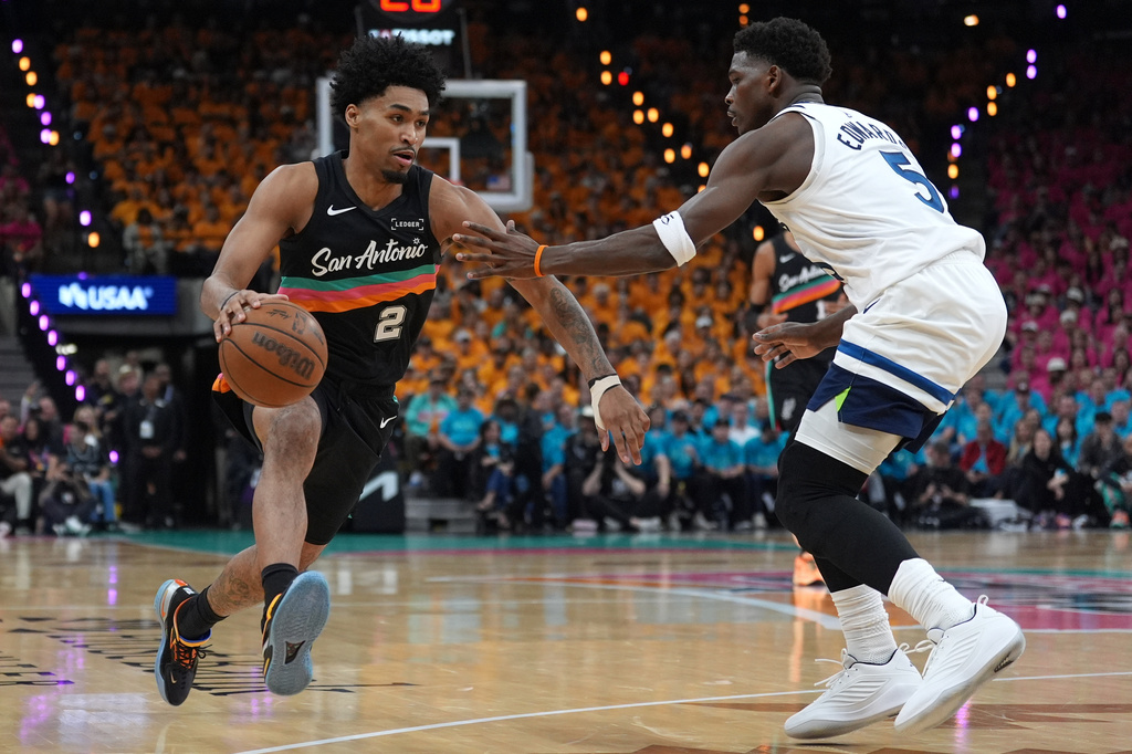 San Antonio Spurs guard Dylan Harper (2) works toward the basket as Minnesota Timberwolves guard Anthony Edwards (5) defends during the first half in Game 1 of a second-round NBA playoffs basketball series in San Antonio, Monday, May 4, 2026. (AP Photo/Eric Gay)