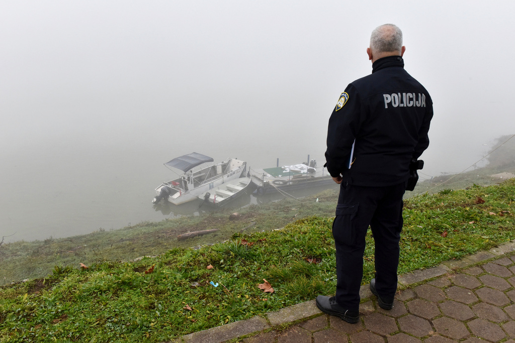 A Croatian police officer looks from the shore of Sava river near the site where a boat carrying migrants from Bosnia overturned in eastern Croatia, in Slavonski Brod, Thursday, Dec. 11, 2025. (AP Photo/Nenad Opacak)