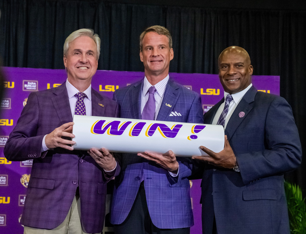 LSU president Wade Rousse, left, and athletic director Verge Ausberry, right, pose with new head football coach Lane Kiffin after after an introductory news conference, Monday, Dec. 1, 2025, in Baton Rouge, La. (Michael Johnson/The Advocate via AP)