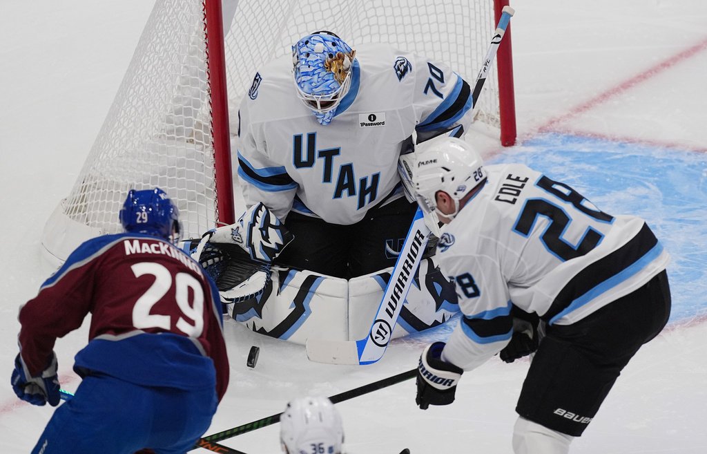 Utah Mammoth goaltender Karel Vejmelka, (70) stops a shot by Colorado Avalanche center Nathan MacKinnon (29) as Mammoth defenseman Ian Cole (28) covers in the first period of an NHL hockey game Thursday, Oct. 9, 2025, in Denver. (AP Photo/David Zalubowski)