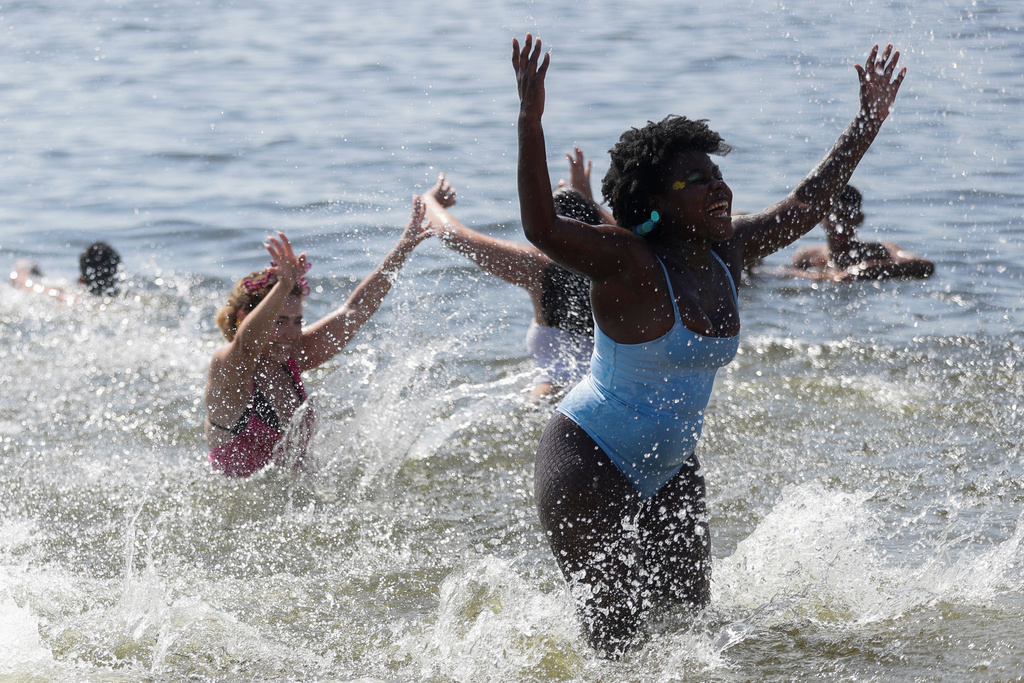 Revelers cool off in the waters of Flamengo beach during the Amigos da Onca Carnival street party, in Rio de Janeiro, Saturday, Feb. 14, 2026. (AP Photo/Bruna Prado)